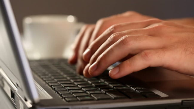 Hands typing at a laptop keyboard.